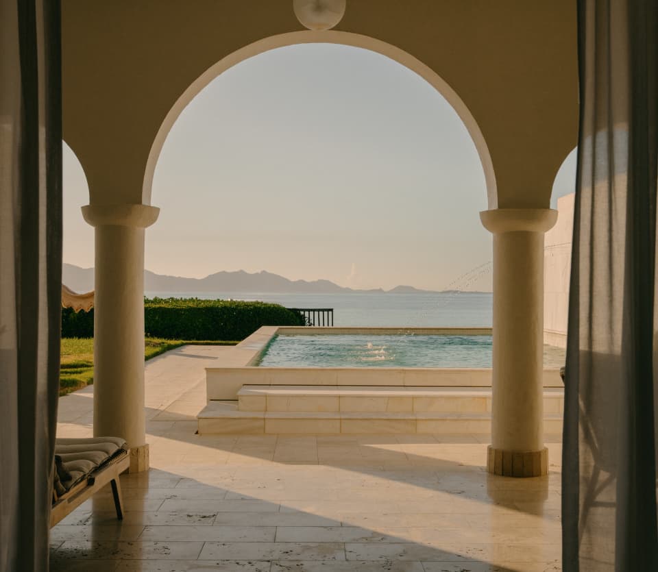 View from the Jonquil Suite through the arches of the serene stone terrace, over the private pool to the ocean blue beyond.