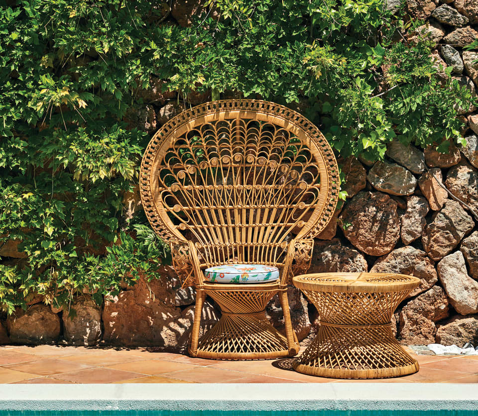Close-up of a stylish bamboo chair and matching coffee table beside an outdoor pool